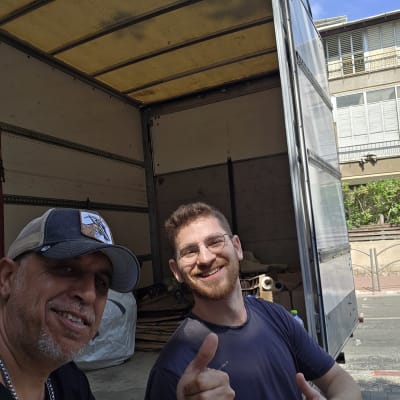 שני אנשים מחייכים ליד משאית פתוחה ברחוב