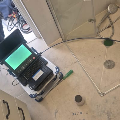 מחשב נייד וכלים על רצפת חדר אמבטיה, קשור לזיהוי נזילות