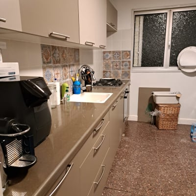 מטבח מאורגן עם ארונות, כיור, מכונת קפה וחומרי ניקוי