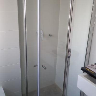 מקלחון זכוכית עם דלתות מתכת וברז מקלחת