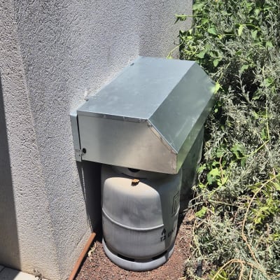 מיכל גז עם כיסוי מתכת ליד קיר חיצוני