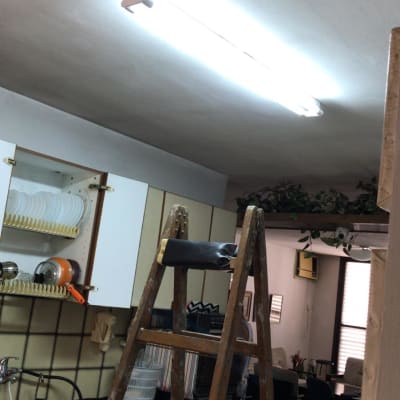 סולם עץ מתחת למנורת פלורסנט דולקת בתקרה