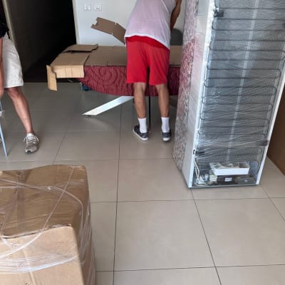 אדם אורז קרטון ליד מקרר עטוף בניילון