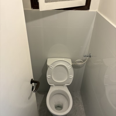 אסלה נקייה בחדר שירותים עם חלון פתוח