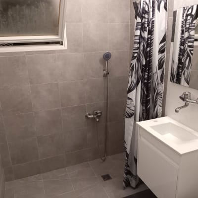 חדר אמבטיה עם אריחים אפורים, מקלחון וכיור לבן