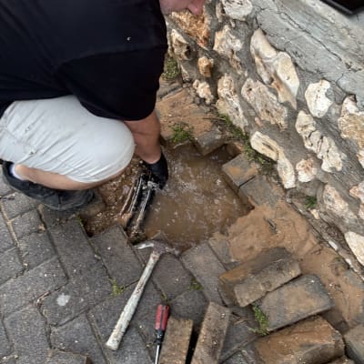 אדם עובד על צינור מים עם כלים על הקרקע