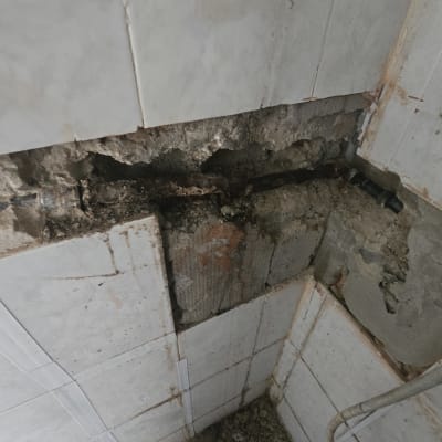 צינור מים חשוף בקיר שבור עם אריחים