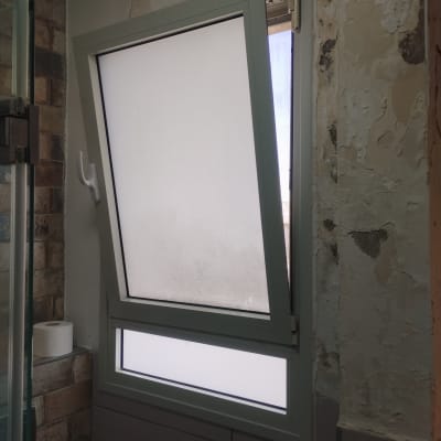 חלון עם תריסים פתוחים למחצה בחדר אמבטיה