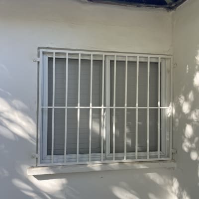 חלון עם סורגים לבנים על קיר חיצוני