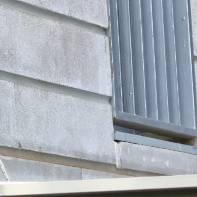 קיר עם סדקים ליד חלון מתכת אפור