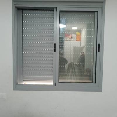 חלון עם תריסים סגורים למחצה על קיר לבן