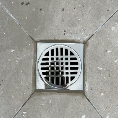 פתח ניקוז מתכת ברצפת בטון אפורה