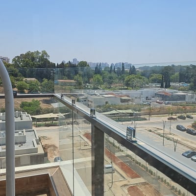 מעקה זכוכית עם תפסנים מתכתיים במרפסת