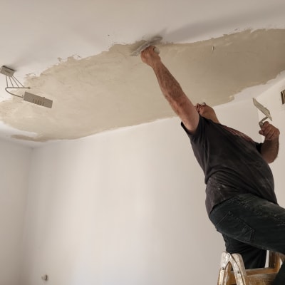 אדם צובע תקרה עם שפכטל וסולם