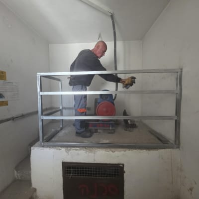 אדם עובד על מסגרת מתכת בחדר קטן