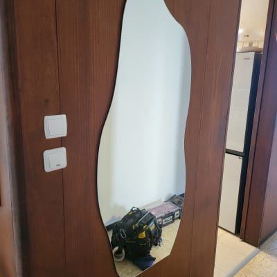 תיק כלים שחור ומזוודה ליד מראה על קיר עץ