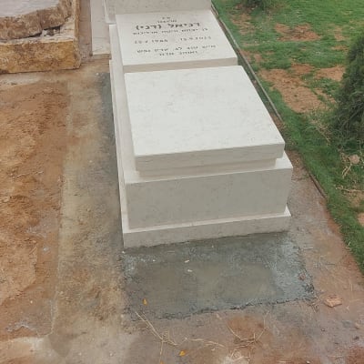 מצבות לבנות עם כיתוב, פרחים על הקרקע