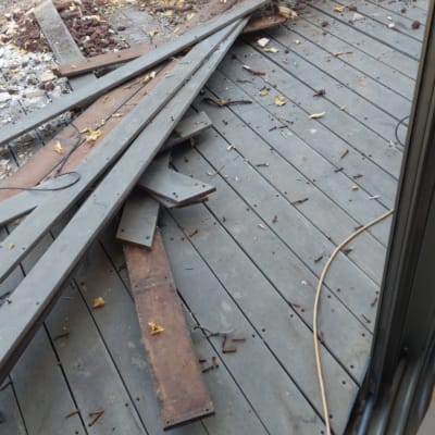 אדם מסיר לוחות עץ ישנים מגג