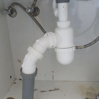 צנרת פלסטיק לבנה מתחת לכיור עם חיבורים