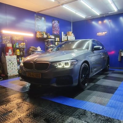 רכב אפור בחדר דיטיילינג עם תאורה חזקה