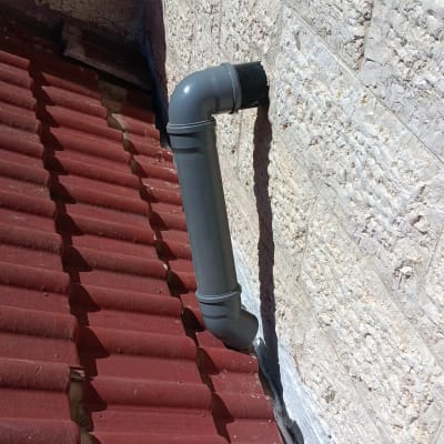 צינור אפור על גג רעפים אדום