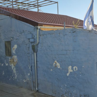 גג רעפים על מבנה עם קיר כחול ודגל ישראל