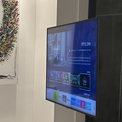 טלוויזיה על קיר עם יצירת אמנות ונעליים על הרצפה