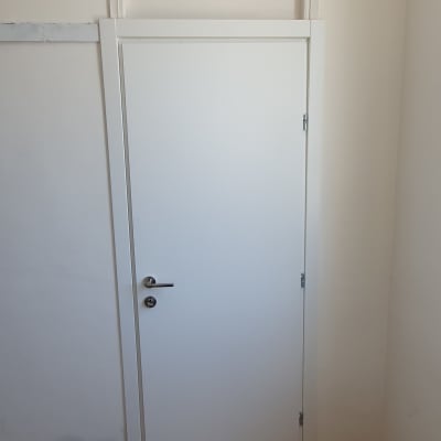 דלת לבנה עם ידית מתכת, מקדחה על הרצפה