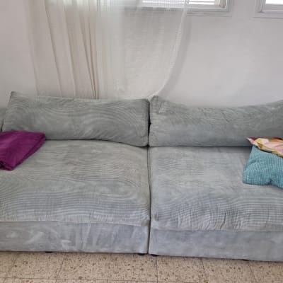 ספה אפורה עם כריות צבעוניות בחדר מואר