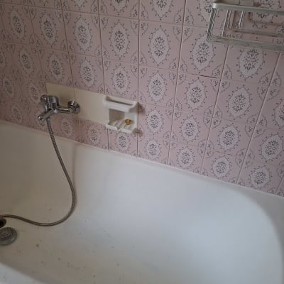 אמבטיה עם אריחים ורודים וברז מקלחת