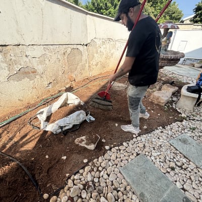 אדם עובד בגינה עם מגרפה, קרקע ואבנים