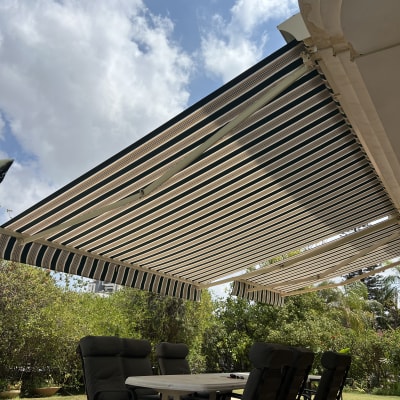 סוכך פרוס מעל שולחן וכיסאות בגינה