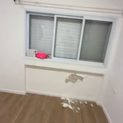 חדר עם קיר פגום ופסולת על הרצפה