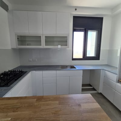 מטבח חדש עם ארונות לבנים ומשטח עבודה