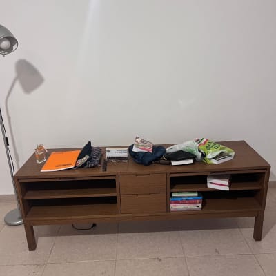 שולחן עץ עם חפצים שונים עליו, כולל ספרים ותיק.