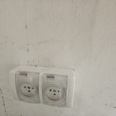 שקע חשמל כפול עם כיסוי שקוף על קיר לבן