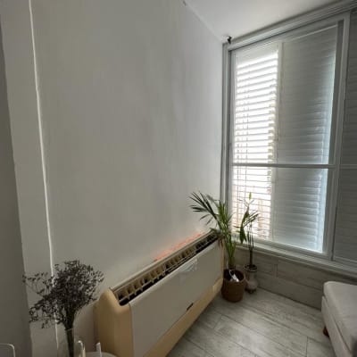 יחידת מיזוג אוויר על קיר ליד חלון עם תריסים