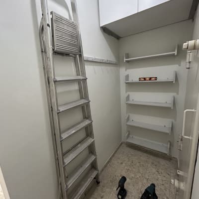 סולם וכלי עבודה בחדר קטן עם מדפים