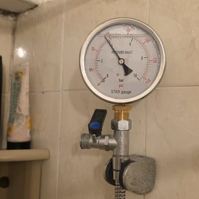 מד לחץ מים מותקן על צינור בחדר אמבטיה