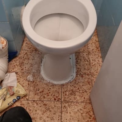 אסלה מותקנת על רצפת קרמיקה עם צינור מאחור