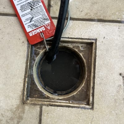 צינור שחור בתוך פתח ניקוז עם שלט אזהרה אדום