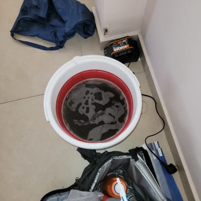 דלי עם מים מלוכלכים ליד תיק כלים ומטען