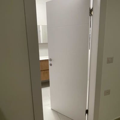 דלת לבנה פתוחה למחצה עם ידית מתכת