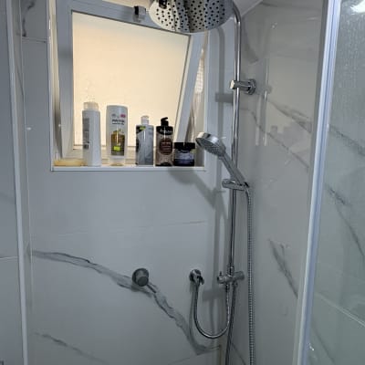 מקלחת עם ראש מקלחת ומוצרים על אדן החלון