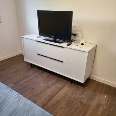 טלוויזיה על שידה לבנה עם שלט ומגבת נייר