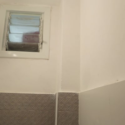 קיר צבוע ליד חלון קטן עם אריחים אפורים