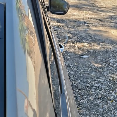 מכונית חונה על שביל חצץ עם השתקפות בשמשה