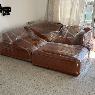 ספה עטופה בניילון בחדר ריק עם וילון לבן