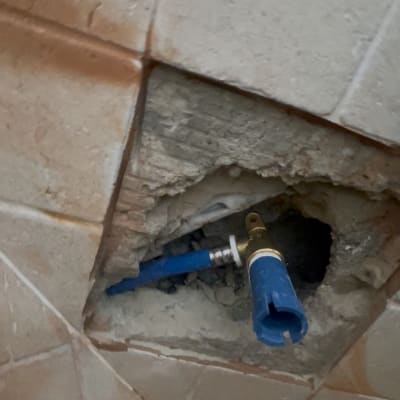 צינור כחול בקיר שבור עם אריחים