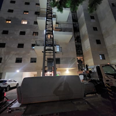 מנוף מרים חפץ מול בניין מגורים בלילה